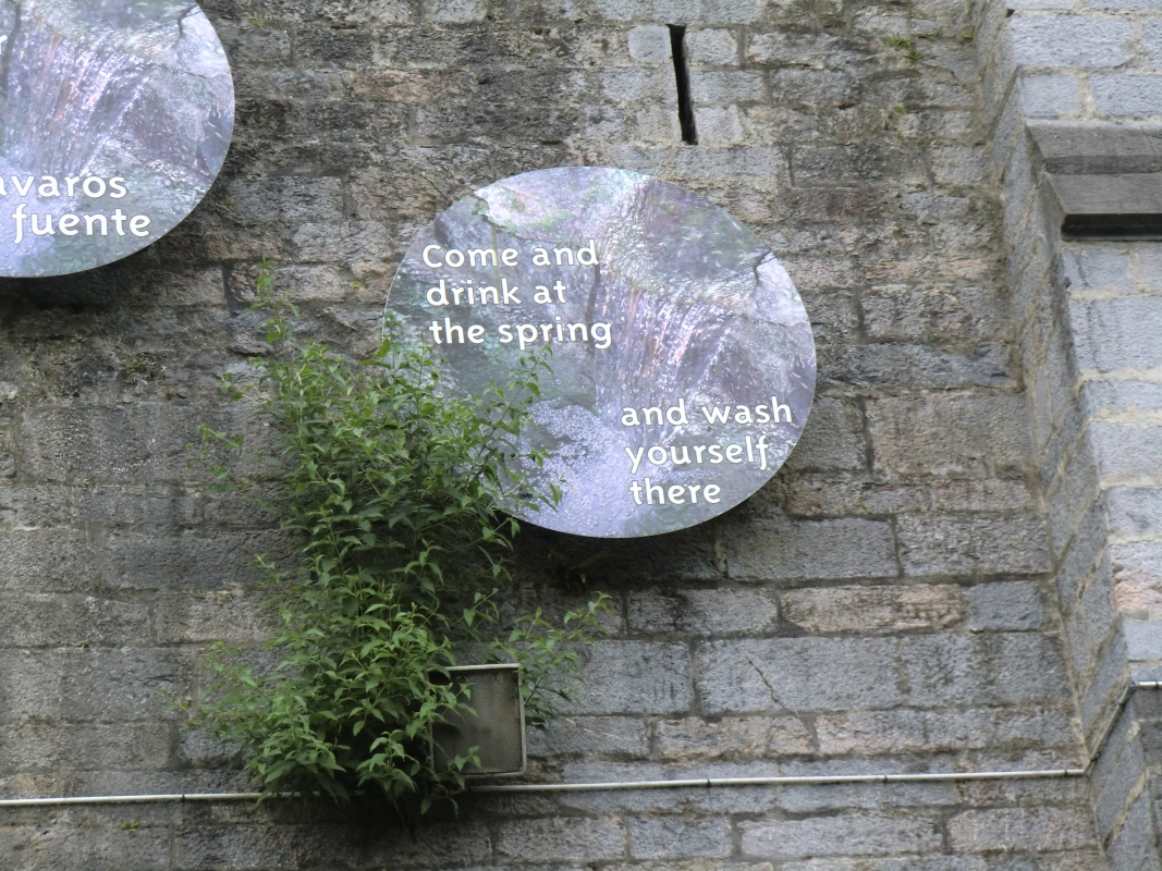 Über den Entnahmestellen, an der Mauer der Basilika der Unbefleckten Empfängnis, die von Maria geoffenbarten Worte „Komm, trink an der Quelle und du wirst gereinigt”